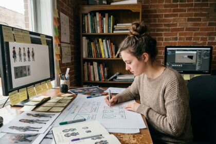 Jeune femme autodidacte en game design esquissant des wireframes de jeux vidéo à son bureau créatif fait maison